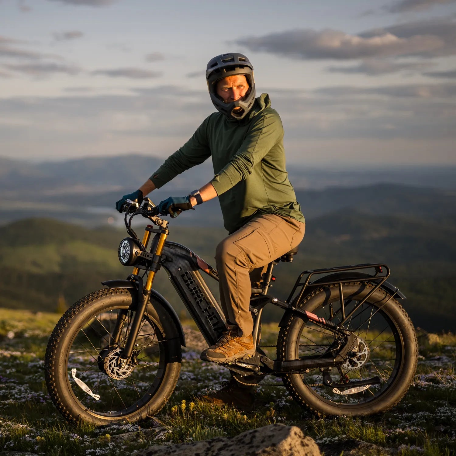 A man riding an HC26 AWD mountain bike on a rugged trail at the summit