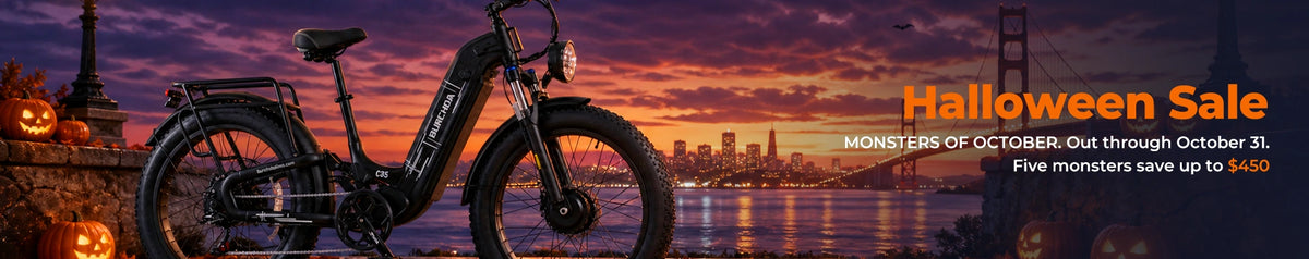 A black electric fat tire bicycle is shown against a dramatic sunset city skyline with Halloween decorations and large sale text reading 'Halloween Sale' on the right.
